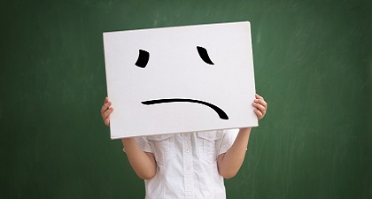 A person holding a cardboard with an unhappy face